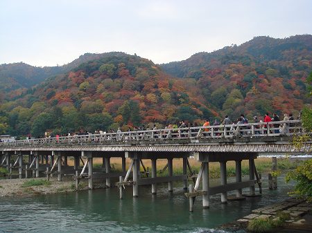 渡月橋を渡る人々と嵐山の紅葉