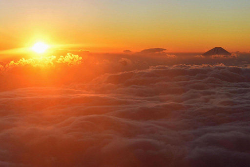 全日空の遊覧チャーター便から見た、富士山（右）の周りに広がる雲海から姿を見せた初日の出
